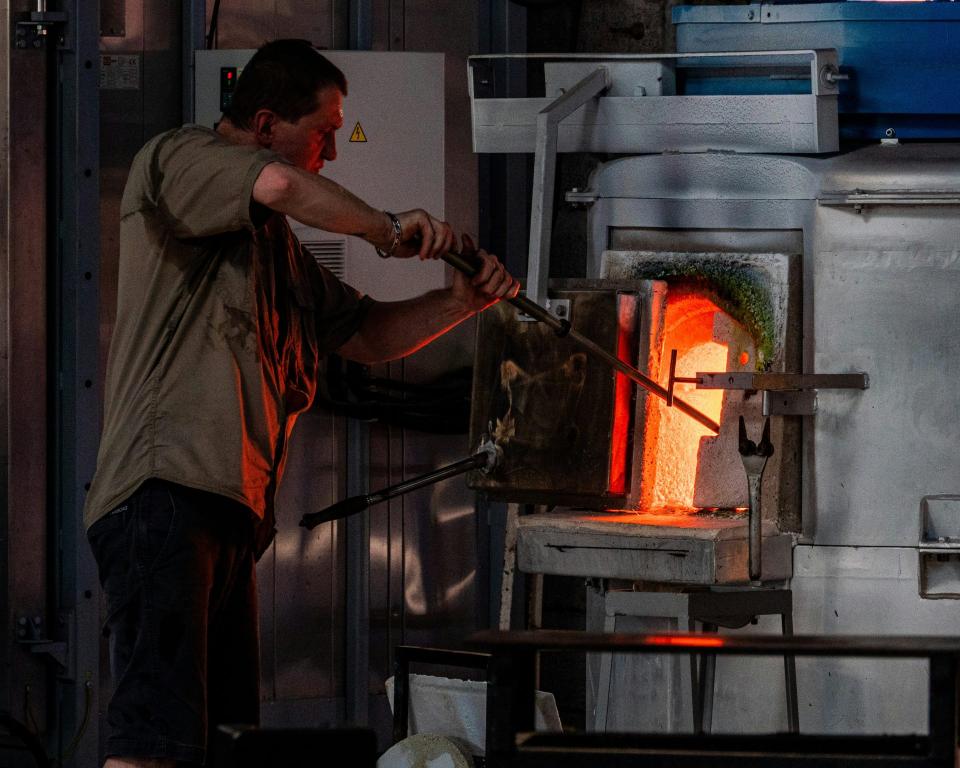 Glassworker using tools to shape heated material